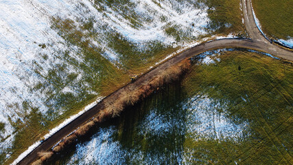 Luftaufnahme von einem Feldweg in einer Viehweide in Bayern im Winter