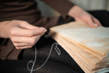 close up of female hands binding book at home or DIY make book with old paper