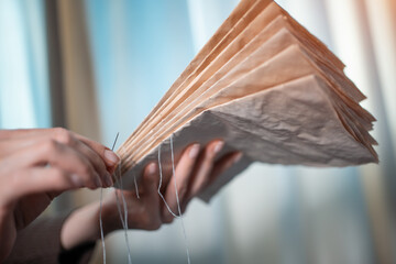 close up of female hands binding book at home or DIY make book with old paper