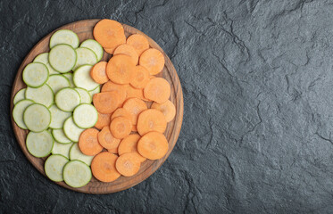 Zucchini and carrot slices on black background