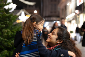 Little girl and her mother outdoor in a city center at Christmas time