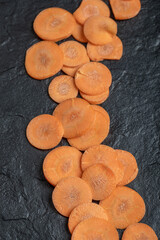 Fresh raw peeled carrot slices. On black background