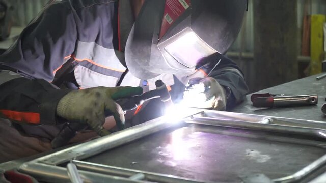 male working welder is engaged in welding the process of obtaining permanent joints by establishing interatomic bonds between the parts to be welded during their local or General heating, plastic defo
