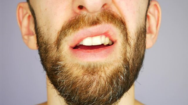 A lower part of a face of a disgruntled man asking WHAT close-up