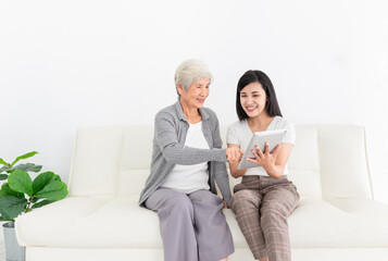 young Asian female and old female search information with tablet computer, they feeling happy and smile, they sitting on sofa, mother's day and happiness family time, technology and social network