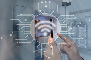 The hand of the man who controls the refrigerator with his smartphone. Internet of Things Concept.