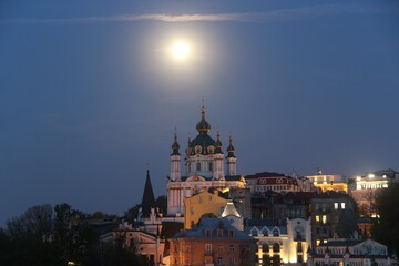 Fototapeta na wymiar St. Andrew's Church was built in the Baroque style in 1749-1754 by the architect Rastrelli. It is located on Andreevskaya Hill above the historical part of Podol. Full Moon. Kiev city.
