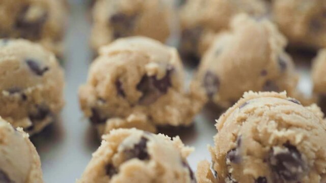 Step by step. Scooping homemade chocolate chip cookies with metal dough scoop to the baking sheet.