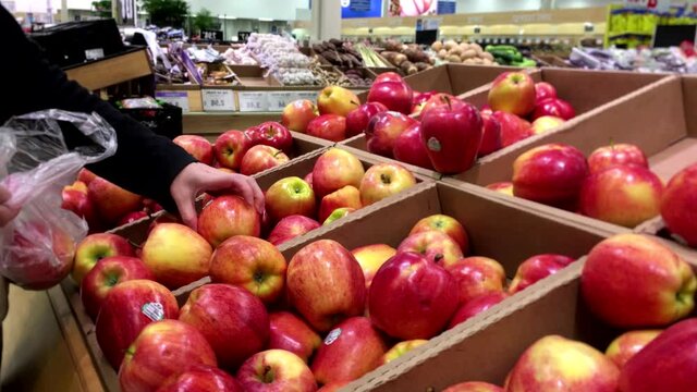 Woman selecting gala apple in grocery store produce department with 4k resolution