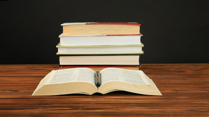 Open book on a stack of books on a table. 