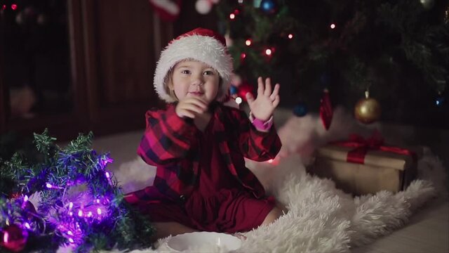 a child in red clothes is sitting waiting for the new year. the concept of celebrating Christmas at midnight. holiday costume