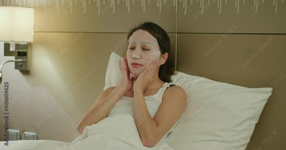 Poster Woman apply face mask and lying on bed at night