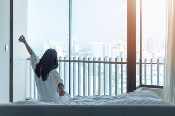 Hotel room comfort with good sleep easy relaxation lifestyle of Asian woman on bed have a nice day morning waking up, taking some rest, lazily relaxing in guest bedroom in city hotel