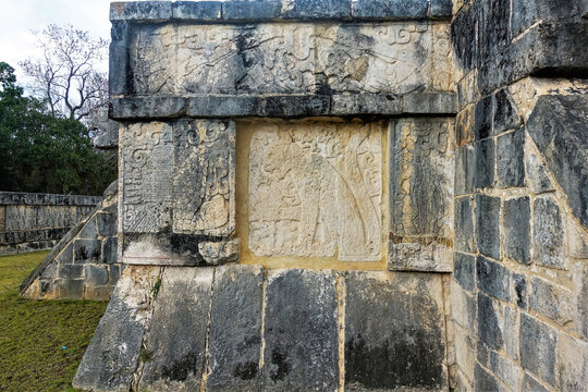 Fragment of a stone ritual platform in the ancient city of Chichen Itza. There are carvings on the walls, images of people, a jaguar. Close-up. Mexico. UNESCO heritage
