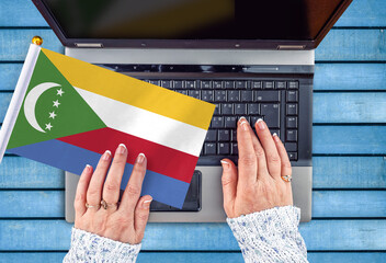 woman hands and flag of Comoros on computer, laptop keyboard
