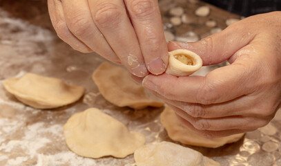 A woman sculpts dumplings from dough.