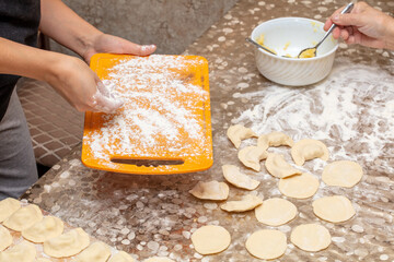 A woman sprinkles flour on a board.