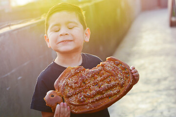 Latin kid with typical big sweet bread named tantawawa for All Saints Day.