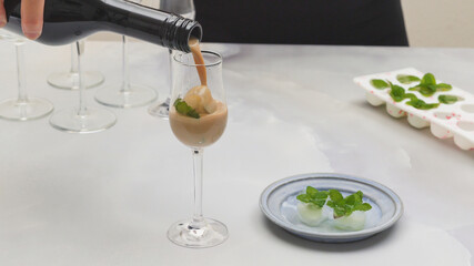 Glass of Irish cream liquor with ice and mint leaves closeup on light grey background