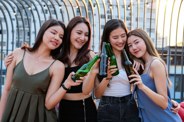 Group of young beautiful Asian girl gang best friends having party at rooftop clinking bottles together.Girls toasting bottles feeling happy enjoy, fun with smile face.