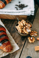 Chocolate croissant on a wooden table with walnuts. Walnuts close-up.