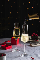 Champagne is pouring in a glass, two glasses on the table