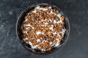 Granola with oatmeal, dried fruit, honey, raisins, chocolate chips, almond and cashew nuts with yogurt in a bowl