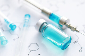 small jars with injection and syringe for injection on a blue background near the chemical formula