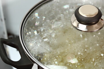 Bubbles of boiling broth under saucepan lid