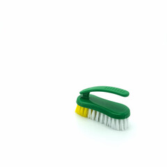 Plastic brush for cleaning the house. Green base, ribbed, non-slip handle. The bristles are thick and long, white and yellow. Isolated on white background. Bottom right corner.