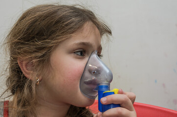 Little girl child makes inhalation with mask on face	