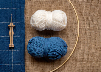 Copy space composition with two wool balls and a wooden punch needle tool on a burlap fabric and a...