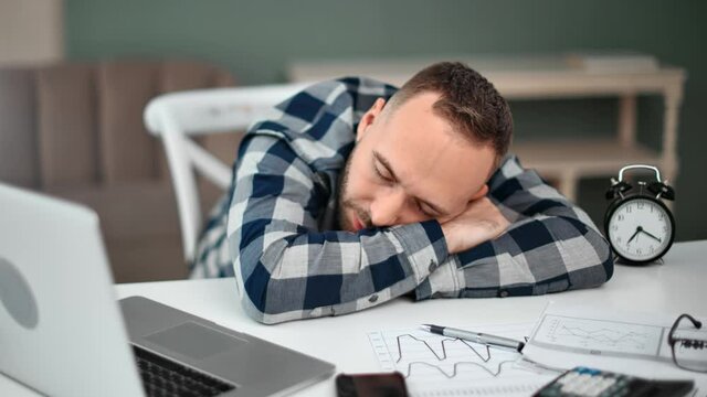 Fatigue inefficient man sleeping lying on table with documents and laptop. 4k Dragon RED camera