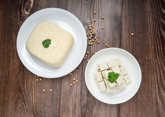 Whole fresh tofu in white plate and Diced Tofu in dish on wood background. full depth of field. vegan food concept. Healthy eating