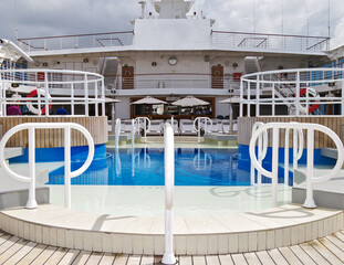 Elegant sun loungers and deck chairs on outdoor swimming pool deck of luxury cruiseship or cruise...