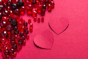 Paper heart cards and cut glass beads on red background