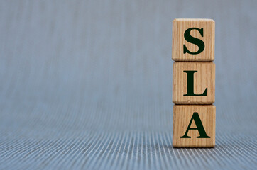 SLA - word on wooden cubes on a gray background