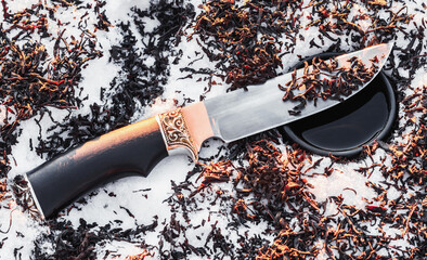 Dried tea leaves on knife blade with thermos mug on the snow