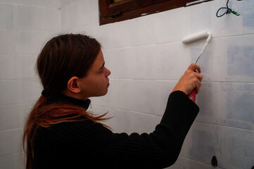 young woman painting bathroom ceramic  wall tiles ,do it your self ,renovation ,