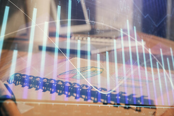 Double exposure of financial graph drawings and desk with open notebook background. Concept of forex market