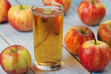 A glass with apple juice and ripe apples