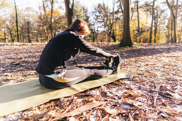 Beautiful woman practiced yoga in autumn or winter in the forest or park. outdoor sport concept