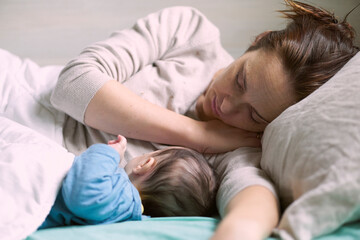 middle-aged woman lying with her two-month-old baby in bed resting. motherhood concept
