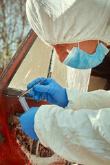 Older red car burned by criminals examined by police technician
