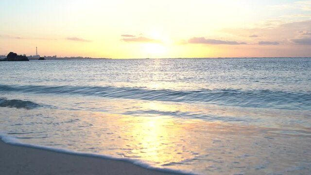 水平線に沈む夕日と砂浜に寄せる波の固定視点動画（35mm）