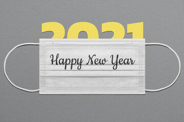 The greeting card concept with the number 2021 under a medical mask with the inscription "Happy New Year"