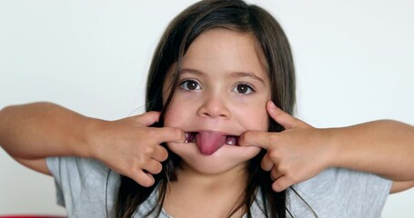 Little girl grimacing, sticking ongue out. Child grimace making funny faces