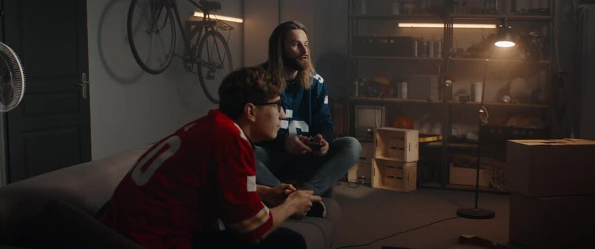  Two Friends Hanging Out, Sitting On Sofa, Playing Video Game Inside Garage. Shot With 2x Anamorphic Lens