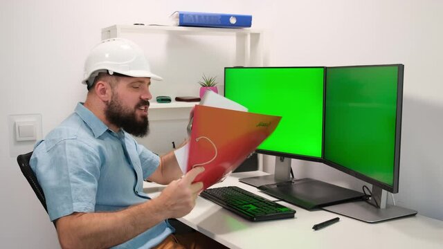 Man in helmet working at home behind computer with two green screens for tracking and pasting Your information. Cozy home interior, high technological concept.