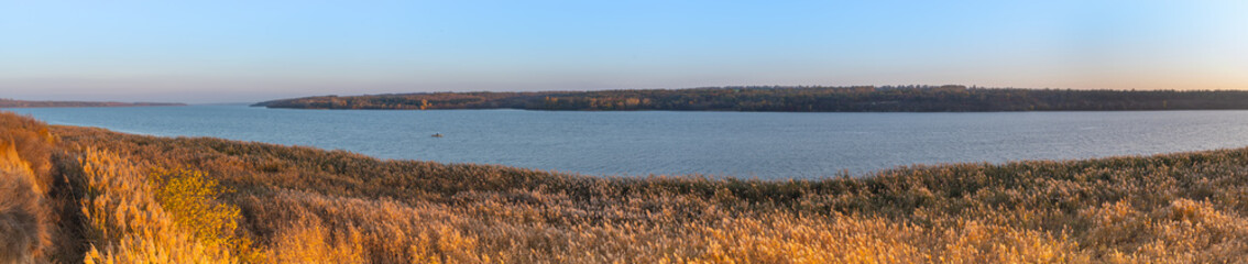 Panorama. Beautiful view of the Dnieper river with green island on blue sky background
